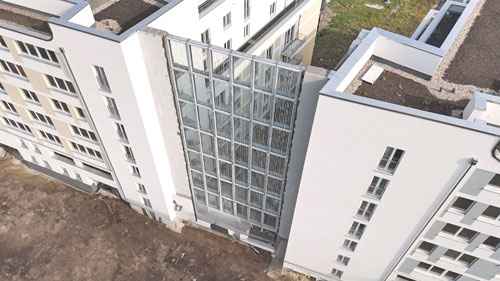 Glas-Lärmschutzwand zwischen mehrstöckigen Wohngebäuden, Blick von oben auf Gebäude und Zwischenraum