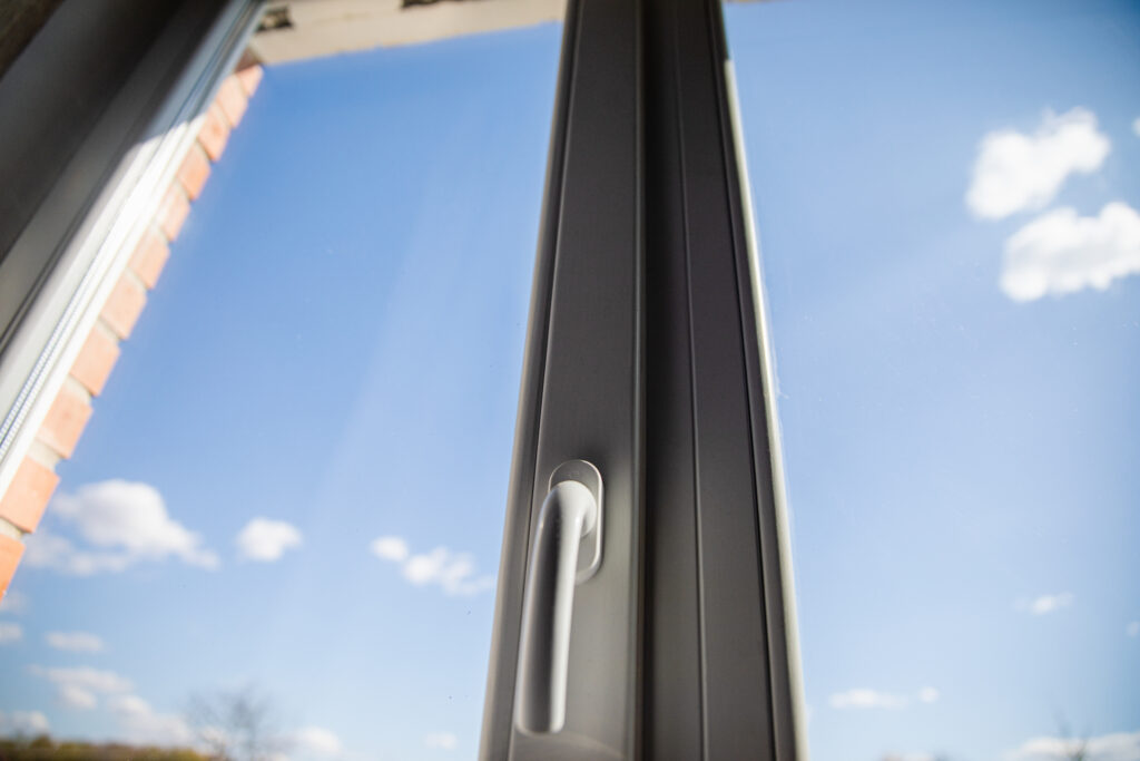 Fensterrahmen mit Griff und Blick auf den blauen Himmel und weiße Wolken