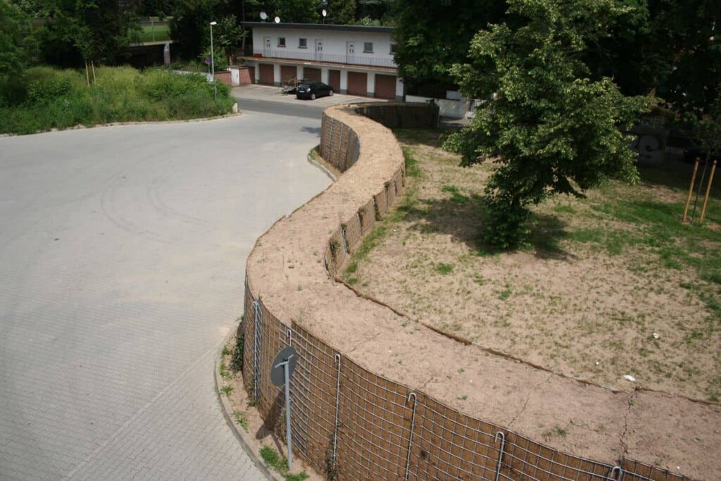 Geschwungene Lärmschutzwand entlang einer Straße in einem Wohngebiet