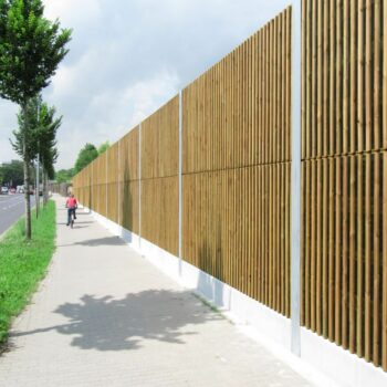 Lärmschutzwand aus Holzpaneelen entlang eines Gehwegs und einer Straße