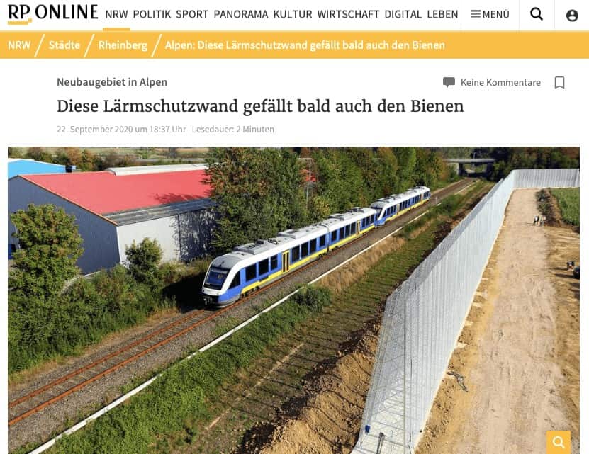 Screenshot eines RP ONLINE-Artikels über eine begrünte Lärmschutzwand neben Bahngleisen, mit Zug im Bild